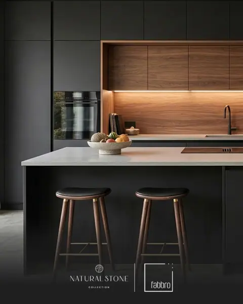 Pale veined stone is used for the kitchen island and work surfaces, alongside dark cabinetry and warm timber details.