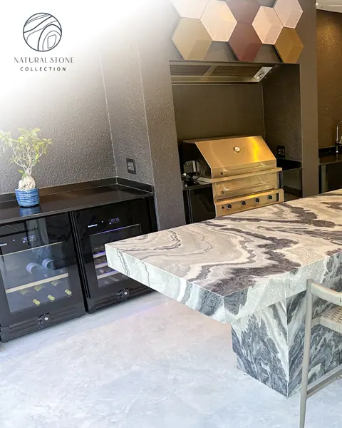 Grey veined stone is used for the kitchen island and work surfaces, alongside dark cabinetry and warm timber details.