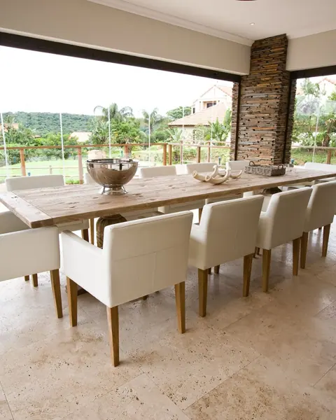 Warm beige natural stone is used for the terrace paving, alongside garden views and relaxed outdoor seating.