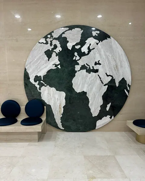 Contrasting natural stone colours is used for the decorative screen and seating area, alongside artwork and sculptural furniture.