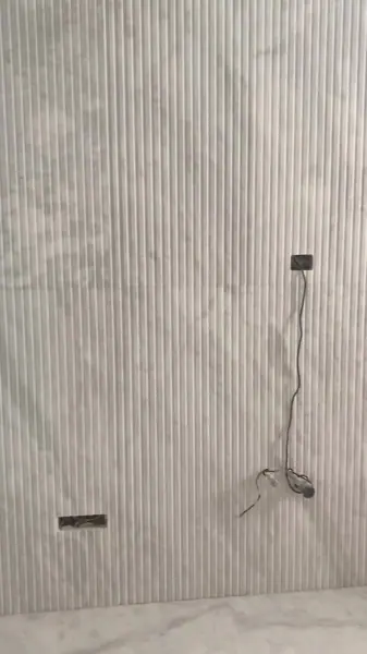 Pale veined stone is used for the shower walls, alongside a textured backdrop and subtle surface variation.