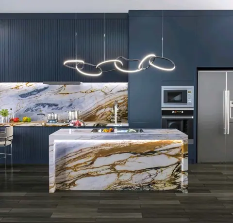 White stone with golden veining is used for the kitchen island and work surfaces, alongside dark cabinetry and warm timber details.