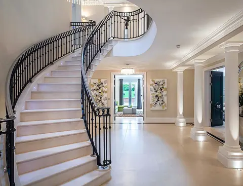 Soft cream stone is used for the stair treads and landings, alongside decorative metal balustrades and a bright stairwell.