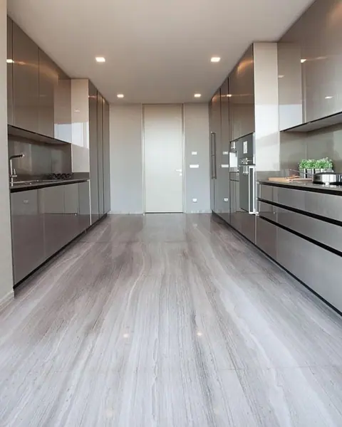 Stone with flowing linear bands is used for the kitchen floor and surrounding surfaces, alongside light cabinetry and warm timber finishes.