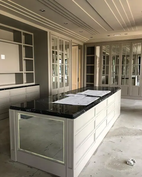 Pale veined stone is used for the vanity and its surrounding surfaces, alongside classical mouldings and decorative lighting.