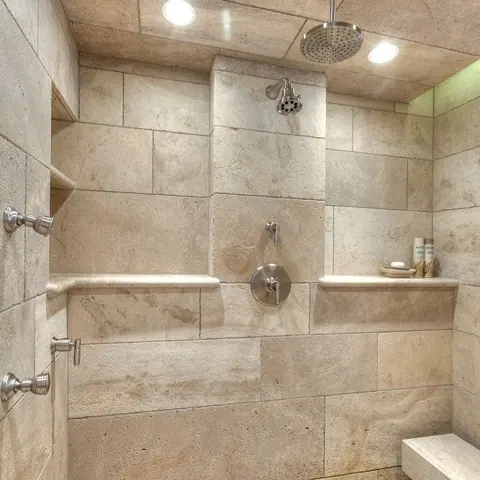 Warm travertine is used for the shower walls, alongside honey coloured walls and a freestanding bath.