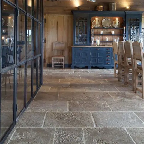 Rustic stone with natural variation is used for the floor throughout the room, alongside wine shelving and a warm, intimate atmosphere.