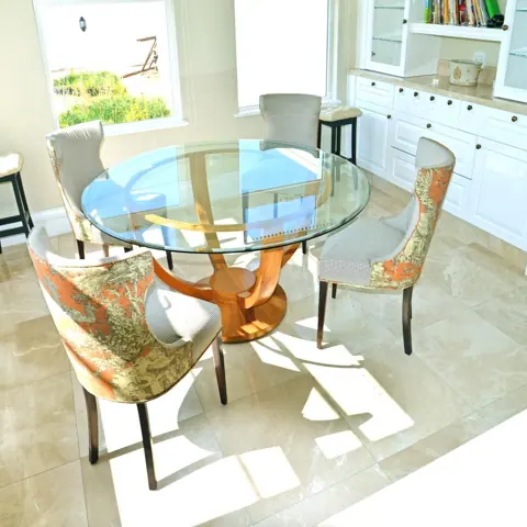Soft cream stone is used for the floor throughout the room, alongside tall windows and a bright neutral interior.