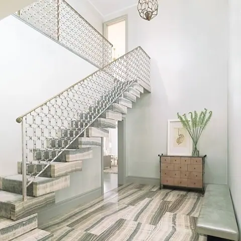 Contrasting natural stone colours is used for the stair treads and landings, alongside decorative metal balustrades and a bright stairwell.