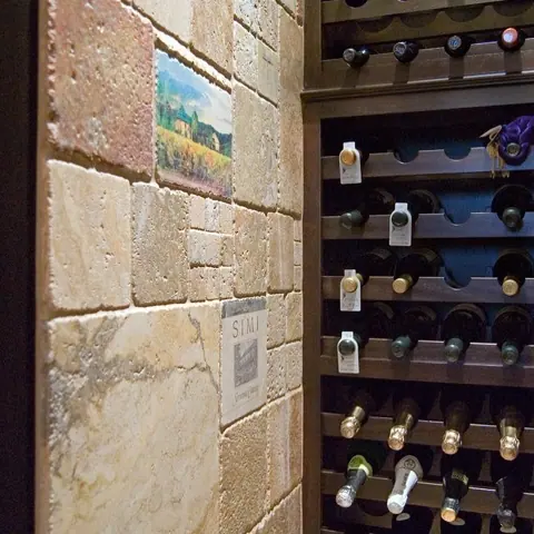 Rustic stone with natural variation is used for the feature wall, alongside wine shelving and a warm, intimate atmosphere.