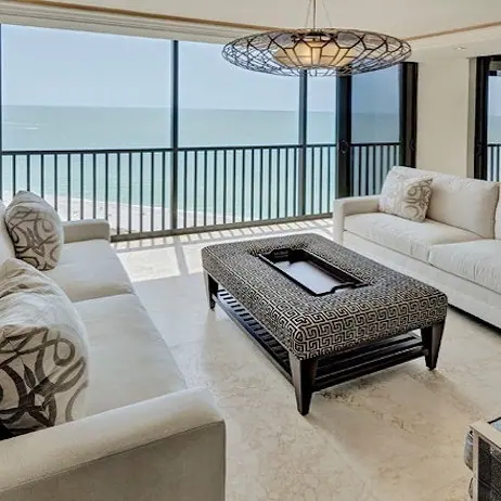 Soft cream stone is used for the floor throughout the room, alongside broad glazing and an expansive distant view.