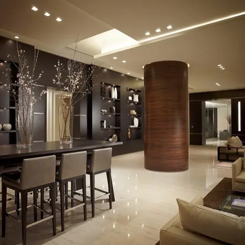 Rich brown veined stone is used for the kitchen floor and surrounding surfaces, alongside dark cabinetry and warm timber details.