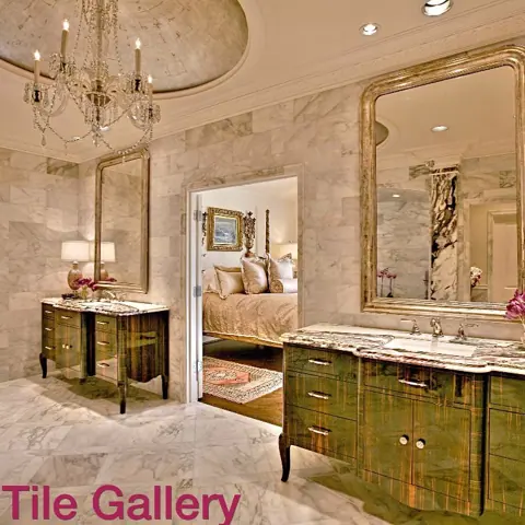 Warm beige natural stone is used for the vanity and its surrounding surfaces, alongside ornate mirrors and traditional decorative details.