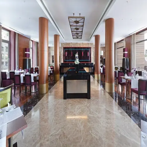 Rich brown veined stone is used for the entrance floor and architectural details, alongside wide glazing and an open connection between spaces.