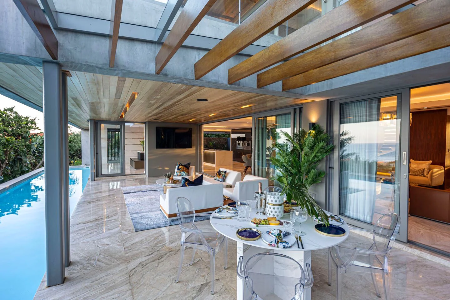 Natural stone flooring beneath a timber and glass canopy beside a swimming pool